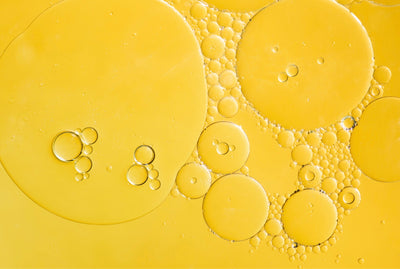 Hair Addicct close-up of rapid hair growth serum and  bubbles on a yellow background